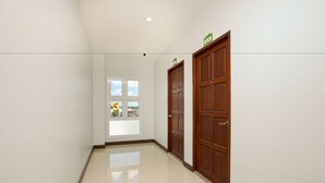 A hallway with two wooden doors, a window with a view, and a ceiling light. - Je t'aime Hotel (Trang)