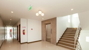 A clean, modern hotel lobby with a polished floor, a staircase, and an elevator. - Je t'aime Hotel (Trang)
