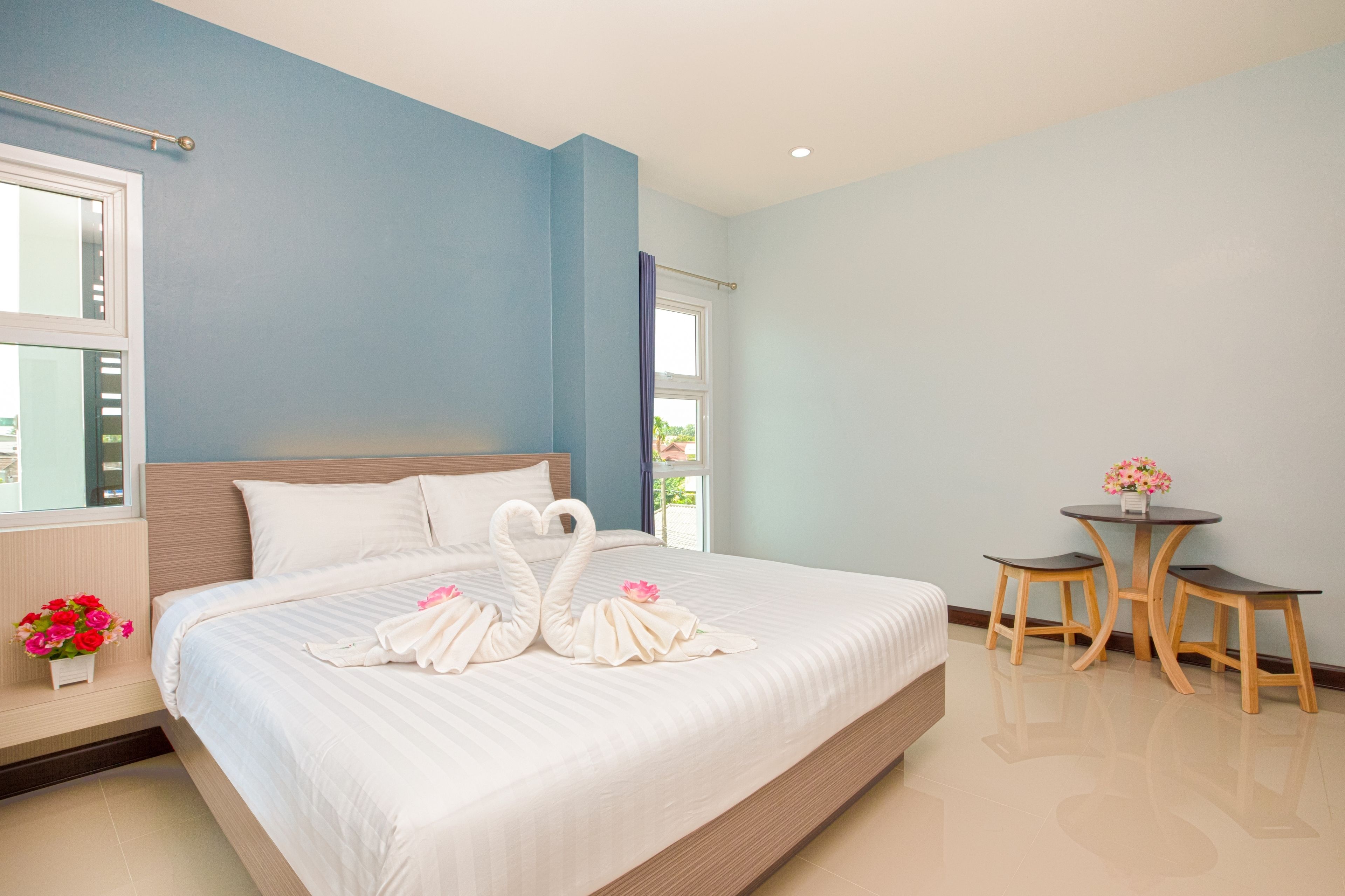 A hotel room with a large bed, a small table, and a window.