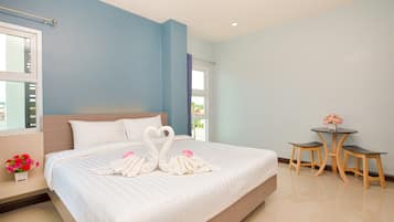 A hotel room with a large bed, a small table, and a window.