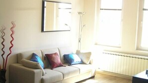 Un salon avec un canapé, une lampe sur pied et un radiateur.