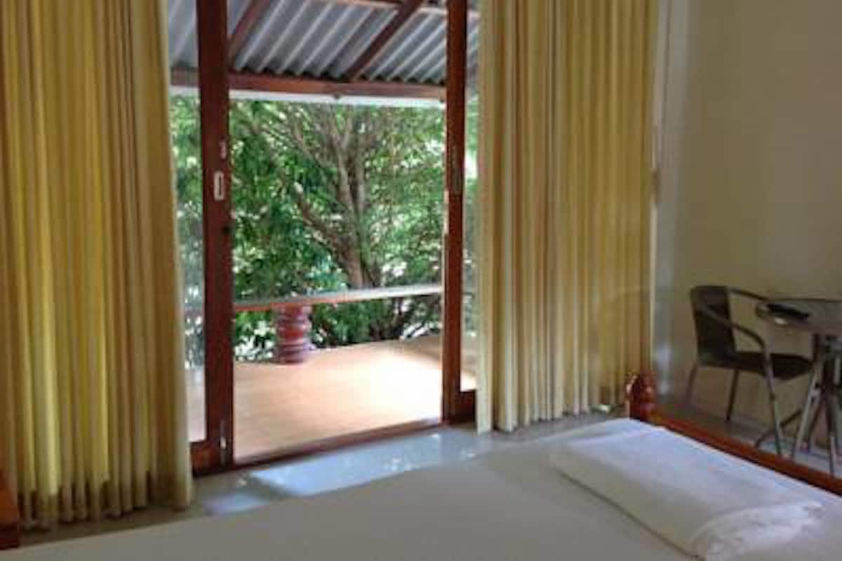Una habitación con cama, una mesa y vista a zonas verdes.