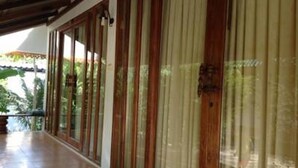 A covered corridor with wooden-framed windows and a tiled floor. - River Park Resort (Yan Ta Khao)