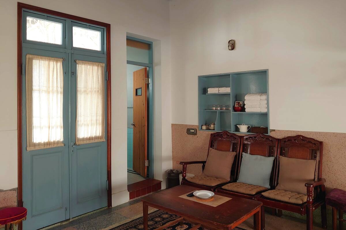 A room with a blue door, a wooden chair, a small table, and a shelf with towels.