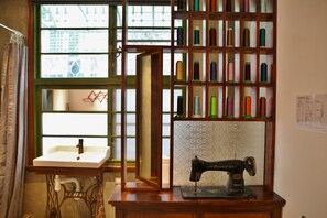 A vintage sewing machine on a wooden table, a shelf with colorful spools of thread, and a window with a view of buildings. - Adore Tainan - Adore Space (Tainan)
