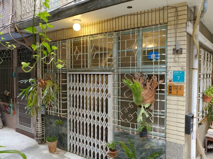 A building with a gated entrance, potted plants, and a sign indicating room number 7.