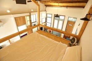 Una habitación con techos altos, un cabecero de madera y un amplio ventanal.