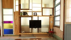 A room with a wooden TV stand, a flat-screen TV, a dining table with a mat, and a window with a view. - Adore Tainan - Adore Space (Tainan)