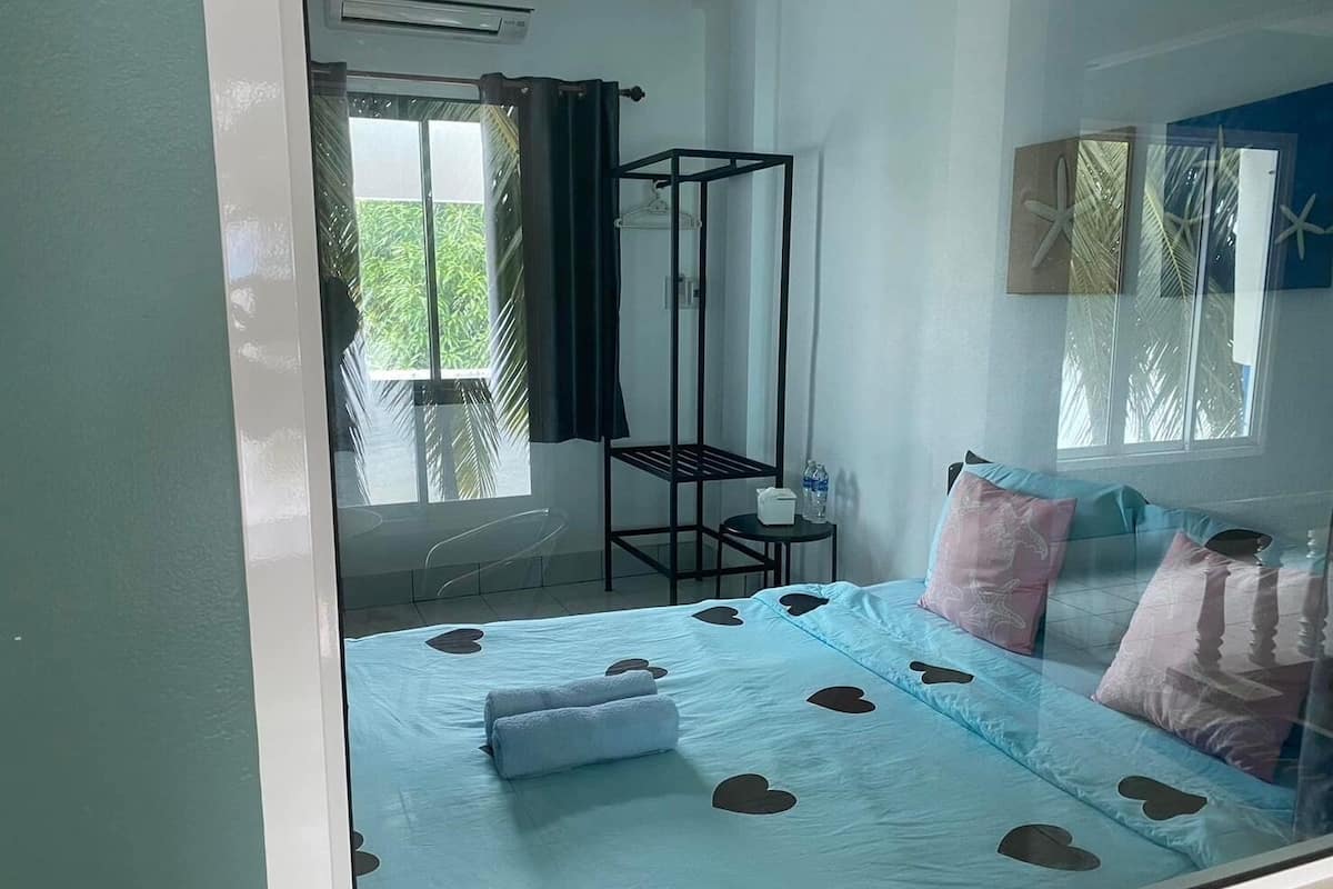Une chambre à coucher avec un lit orné de découpes en forme de cœur, une petite table avec une bouteille d’eau et une chaise.