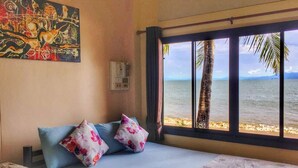 Un dormitorio con cama, almohadas, un cuadro y ventana con vista al mar.