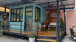 Un edificio pequeño y moderno con un espacio de estar exterior cubierto y un letrero que dice "Suansos Beach".