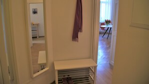 Un couloir avec un meuble à chaussures, un miroir et une porte donnant sur un coin repas.