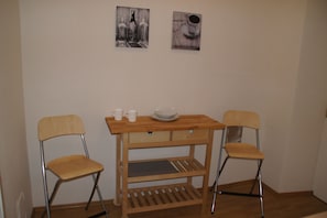 A small wooden table with two chairs, a bowl, and two cups on it.