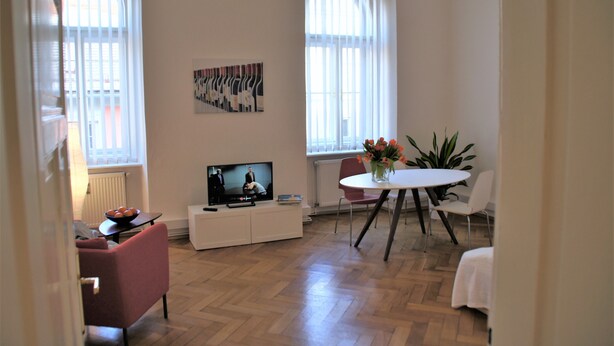 Un salon moderne avec un téléviseur à écran plat, une table à manger avec des chaises et une plante en pot.