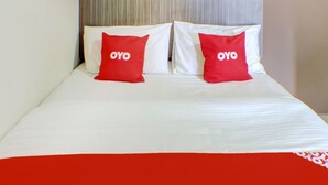 A hotel room with a bed featuring two red pillows with the word "OYO" on them. - OYO 89985 Js Hotel (Johor Bahru)