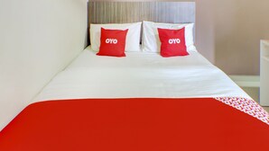 A neatly made bed with white and red bedding, two red pillows with the word "OYO" on them, and a white headboard. - OYO 89985 Js Hotel (Johor Bahru)