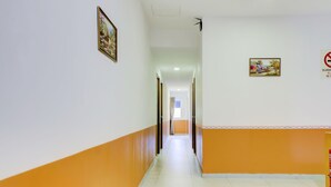 A corridor with white and orange walls, a tiled floor, and a door at the end. - OYO 89985 Js Hotel (Johor Bahru)