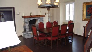 Ein Esszimmer mit Holztisch und roten Sitzmöbeln, einem Kamin und einer Chandelüster.
