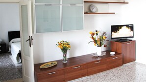 A room with a wooden cabinet, a television, and a clock on the wall.