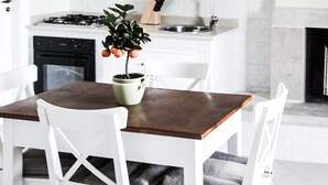 A modern kitchen with white cabinetry, a gas stove, a sink, and a dining area with a table and chairs.