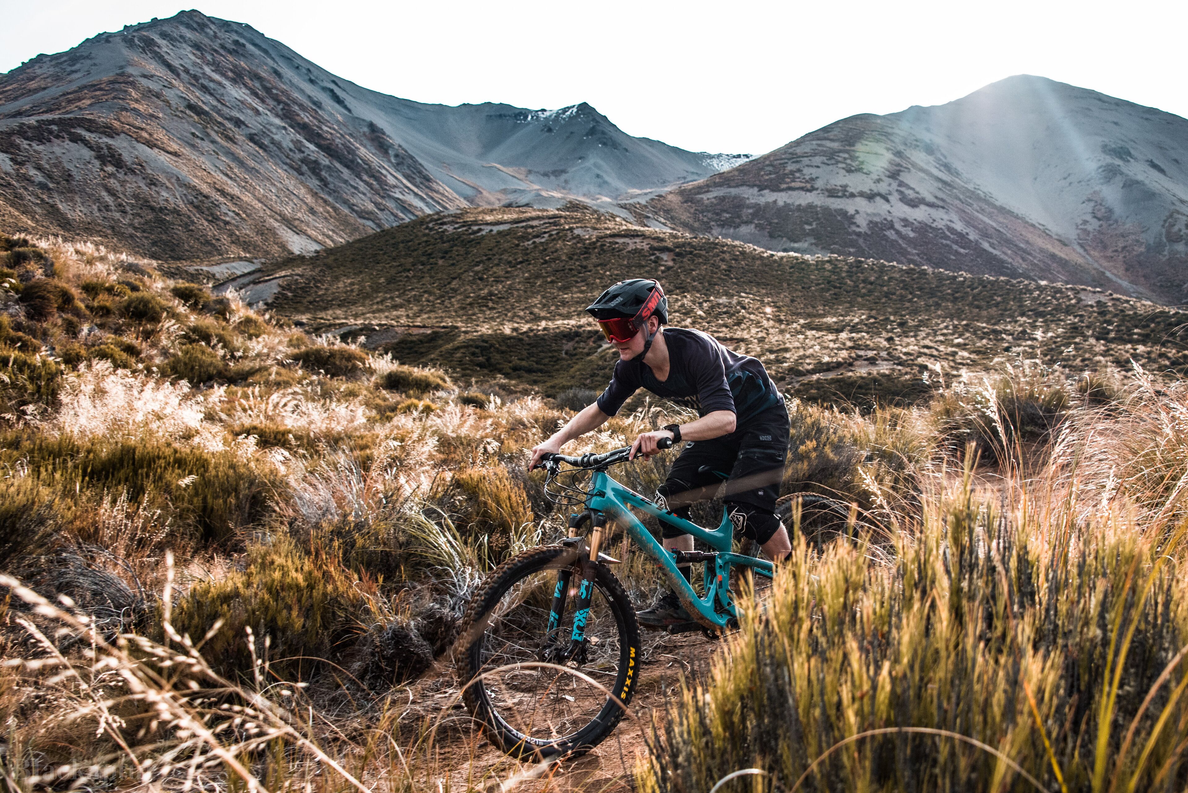 Ciclista de montaña en un sendero, con una montaña al fondo.