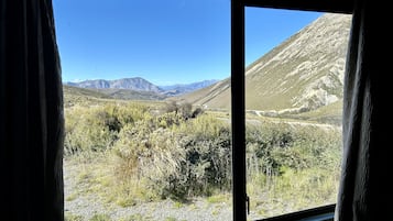Vista desde una ventana a un paisaje montañoso con cielo despejado.