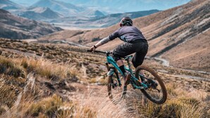 A mountain biker on a trail with a view of distant mountains. - Porters Lodge (Castle Hill)