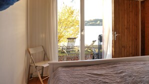 A bedroom with a large sliding glass door leading to an outdoor area with a chair and table. - Vacation home on Pilsensee with direct lake access, jetty and sauna (Herrsching am Ammersee)