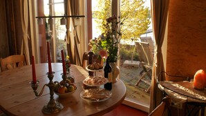 A dining table with a candle holder, fruit bowl, and a vase with flowers. - Vacation home on Pilsensee with direct lake access, jetty and sauna (Herrsching am Ammersee)