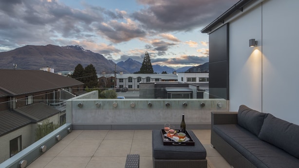 A rooftop terrace with a dining set, a bottle, and a scenic mountain view. - 15 Melbourne by Staysouth (Queenstown)