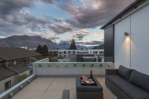 Une terrasse sur le toit avec un ensemble de mobilier de jardin, une bouteille et une vue panoramique sur les montagnes.