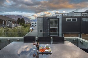 Une table à manger avec vue sur les montagnes, une bouteille de vin et une assiette de fromage et de légumes.