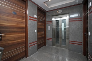 A modern elevator with a metallic finish and a wooden door. - OYO 9028 Hotel Blu Pebbles (New Delhi)