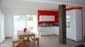 A modern kitchen with white cabinets, a red accent wall, and a brick column. - HOUSE with Jacuzzi 200 m grau beach CAP D'AGDE  (Agde)