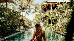 A woman sitting by a pool surrounded by lush greenery and tropical plants. - Sand in My Shoes Beach Loft (Ko Pha-ngan)
