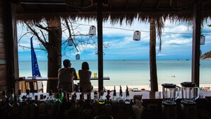 A bar with a view of the beach, bottles, and a blender. - Sand in My Shoes Beach Loft (Ko Pha-ngan)