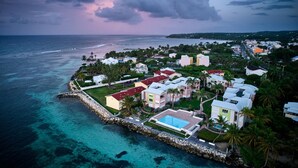 Vista aérea de una zona residencial costera con casas, una piscina y un rompeolas rocoso.