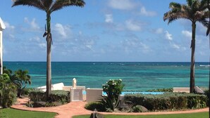 Un camino conduce a una zona de piscina con palmeras y vistas al océano.