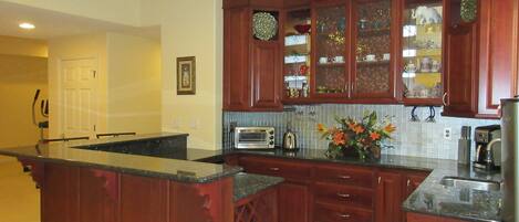 A kitchen with wooden cabinets, a built-in island, and a tiled backsplash.