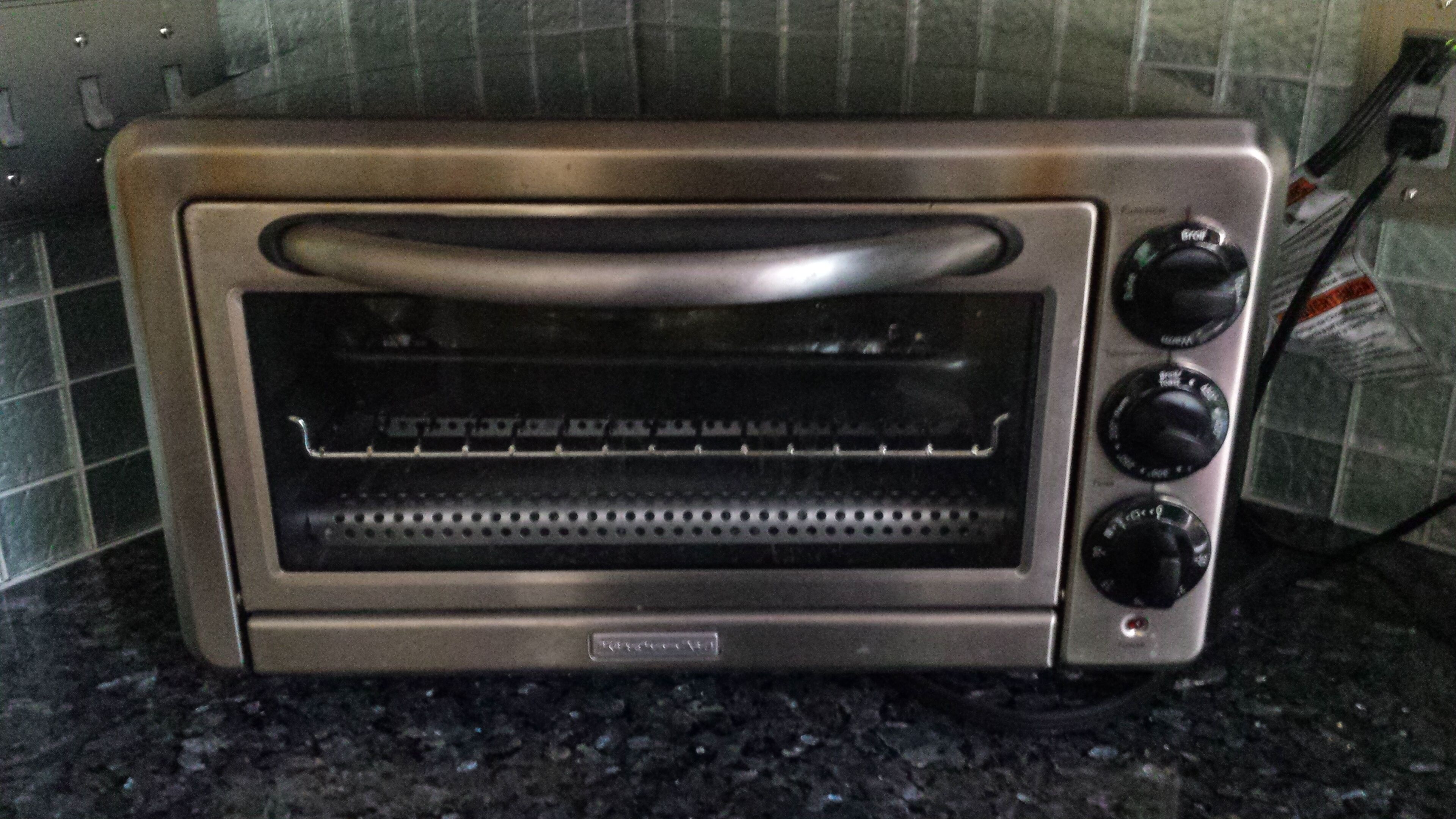 A toaster oven with a control panel, placed on a kitchen counter.