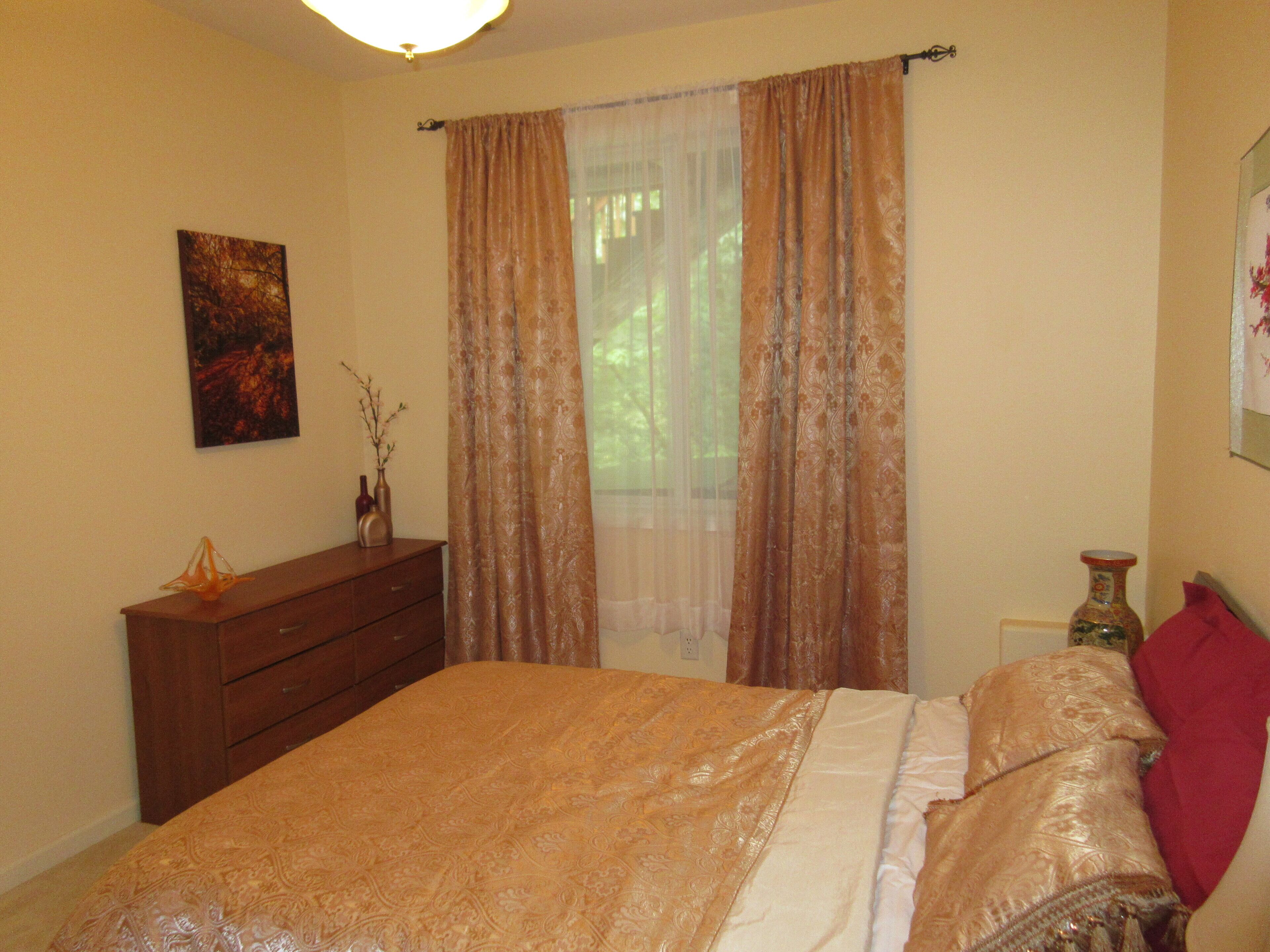 Een slaapkamer met een bed, een dressoir, een vaas en een schilderij aan de muur.