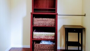 A room with a wooden bookshelf against a wall, a small black table, and a wooden floor.