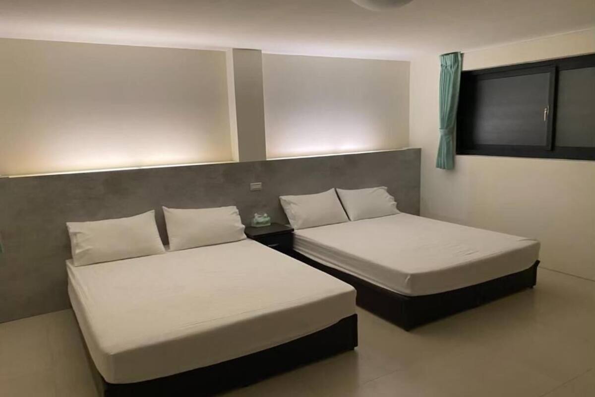 Ein modernes Schlafzimmer mit zwei Einzelbetten, einem Nachttisch und einem Fenster mit Vorhängen.