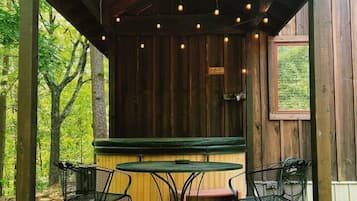 Relax in this serene outdoor seating area with a central table and four chairs, surrounded by lush greenery.
