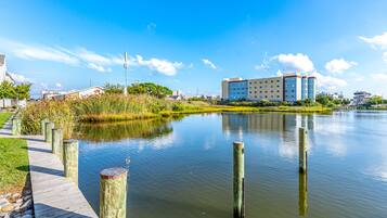 Ein Hotel direkt am Wasserufer mit einer Anlegestelle und Holzpfählen, umgeben von viel Grün und blauem Himmel.