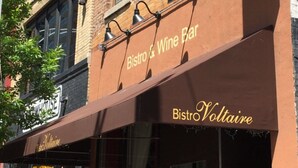 A brick building with a storefront for Bistro Voltaire.