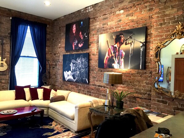 A living room with a brick wall, a sofa, a coffee table, and a TV.