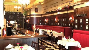 A restaurant with a bar area, red booths, and a checkered floor.