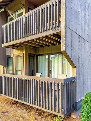 A two-story building with a balcony, large windows, and a wooden deck.