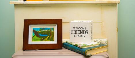 A shelf with a framed picture, a book titled 'Welcome Friends & Family', and a decorative pumpkin sign.
